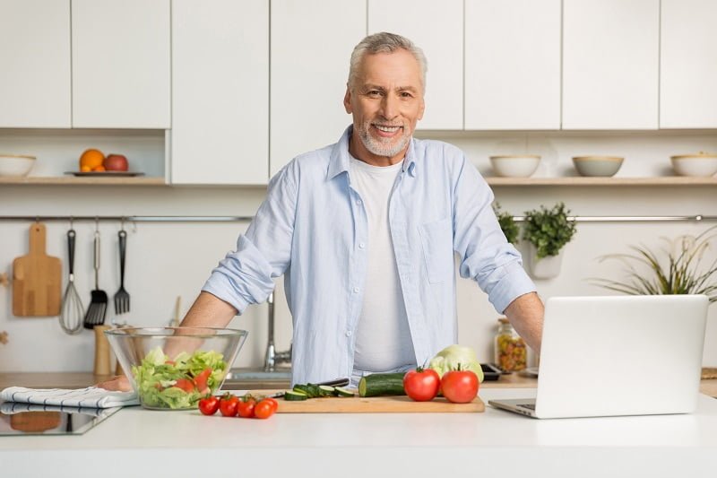 Mature attractive man standing at the kitchen cooking
