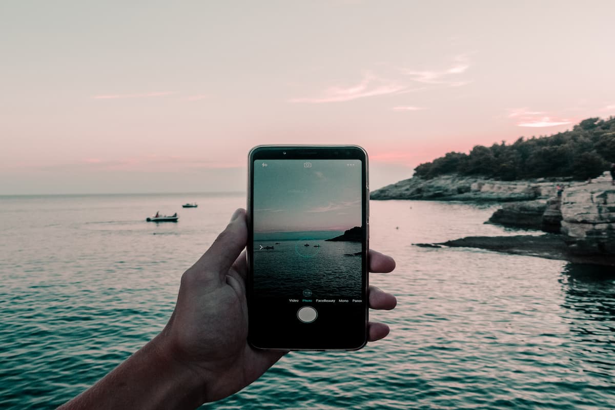 fotograf pozand un peisaj marin cu un telefon